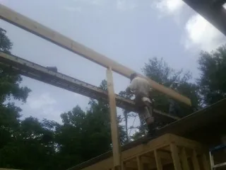 Carpenter setting a ridge beam over a new addition frame — Ice Dam Removal by Roofing Brothers in Bedford Hills