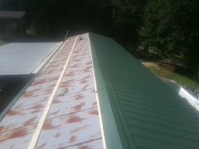 Old rusted panels beside newly installed green metal roofing — Wind Damage Roof Repair by Roofing Brothers in Bedford Hills
