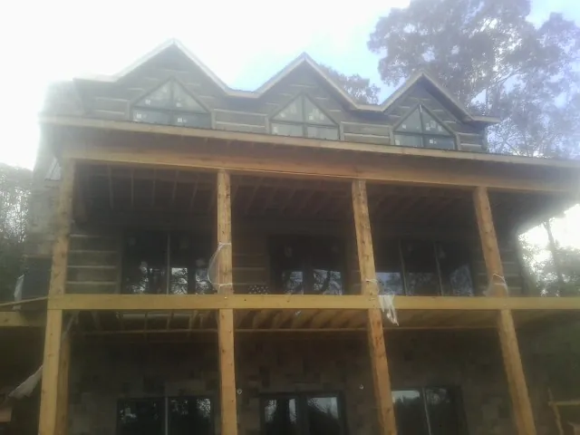 Dormers and porch framing on a large log home under construction — Roof Coating work by our crew in Bedford Hills
