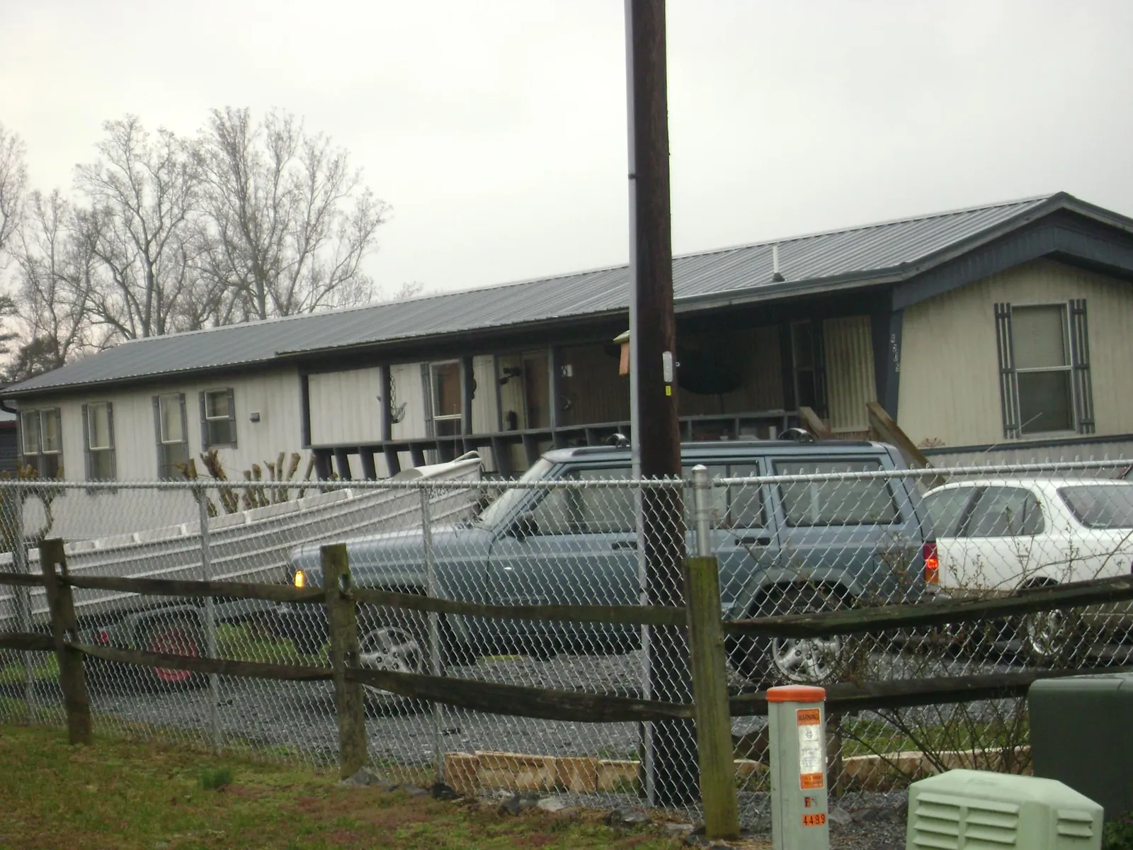 Dark metal roof on a long single story building behind a chain link fence in Bedford Hills