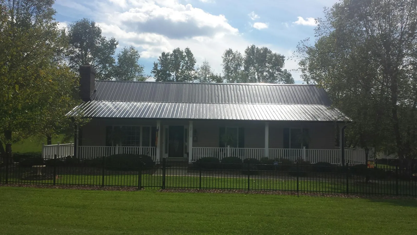 Gray metal roof on a brick ranch with a full width front porch — Gutter Guard Installation work by our crew in Bedford Hills