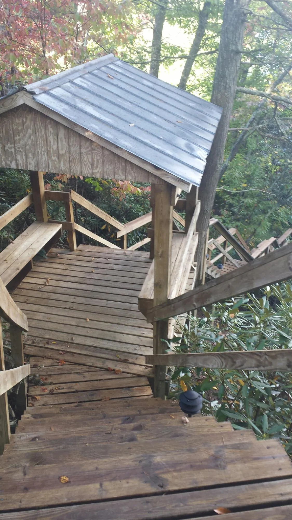 Metal roofed shelter over wooden steps on a wooded walkway — Skylight Repair & Installation work by our crew in Bedford Hills