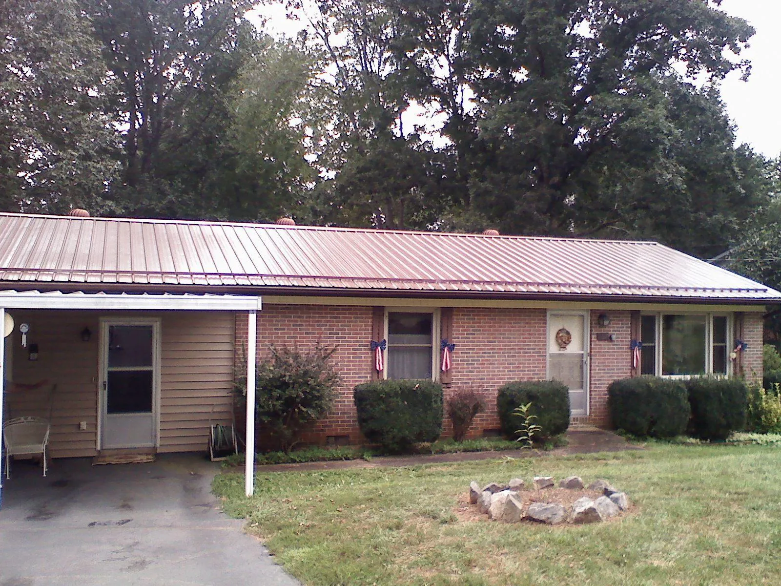 Bronze metal roof and carport on a brick ranch home — Roof Repair work by our crew in Bedford Hills